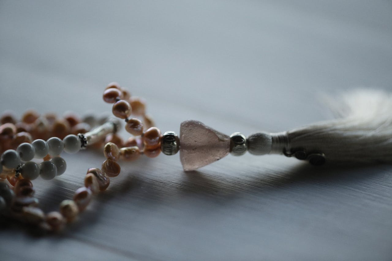creative-03 Close-up of a pearl and gemstone necklace with a tassel, highlighting detailed craftsmanship.